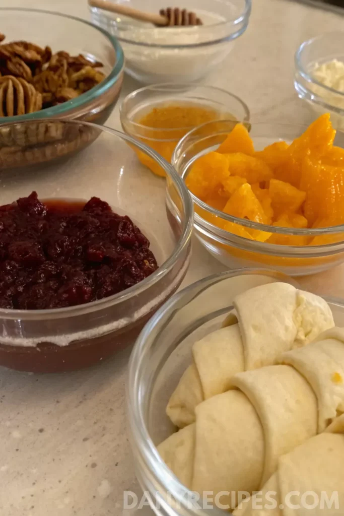 Best Cranberry Cream Cheese Crescent Bites 14 Ingredients for cranberry cream cheese crescent bites, including crescent rolls, cranberry sauce, peaches, pecans, honey, and cream cheese.