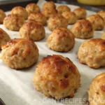 Golden brown Bisquick sausage balls arranged neatly on a baking sheet lined with parchment paper.