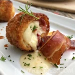 Melty Boursin cheese oozing from crispy prosciutto wrap, garnished with herbs and sauce.