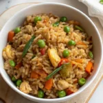 Bowls of vegetable fried rice filled with peas, carrots, bell peppers, broccoli, and green beans, seasoned and stir-fried.