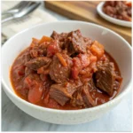 Bowl of slow cooker beef ragù with tender beef chunks simmered in rich tomato sauce.