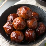 Sweet & Sticky Teriyaki Meatball 12 Sweet and sticky teriyaki-glazed meatballs served in a black bowl with chopsticks.