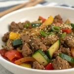 Lean beef skillet with peppers and onions garnished with sesame seeds.